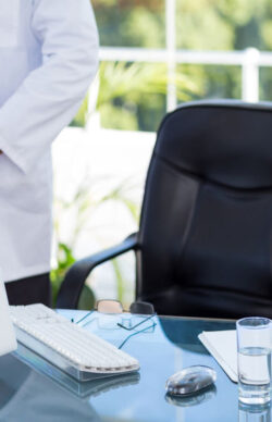 Doctor standing next to his desk in medical office